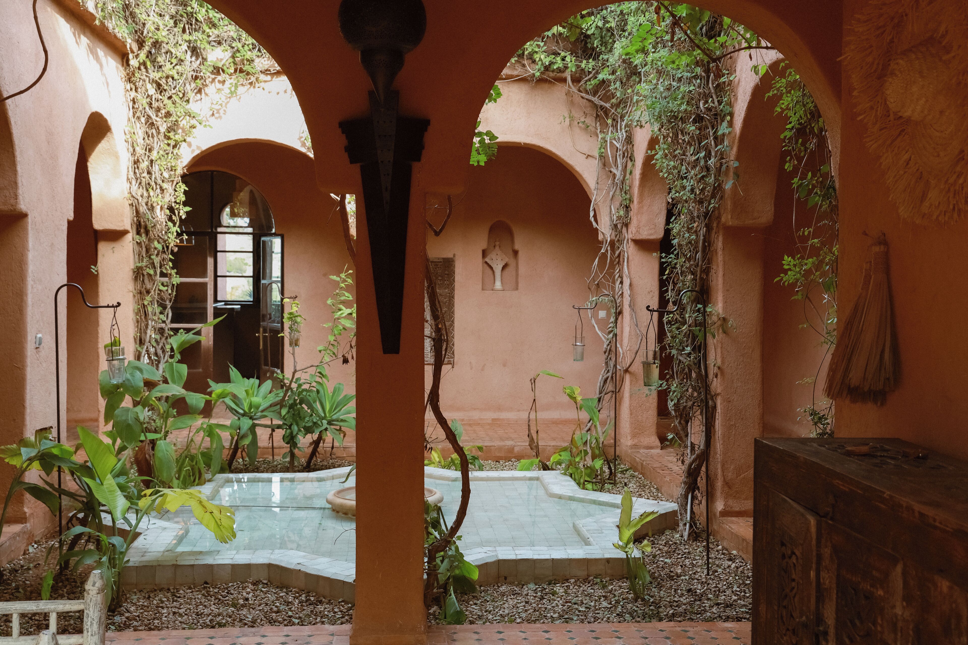 Un patio con arcos, una fuente y plantas en macetas.