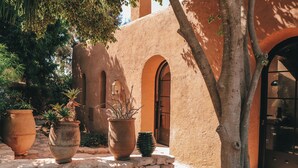 A courtyard with a stone wall, large terracotta pots, and a tree. - Le Jardin Des Douars (Aguerd)