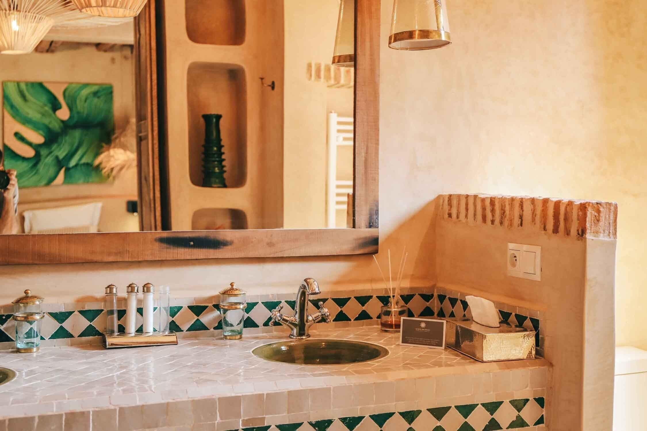 A bathroom with a large mirror, two sinks, a towel rack, and a decorative shelf.
