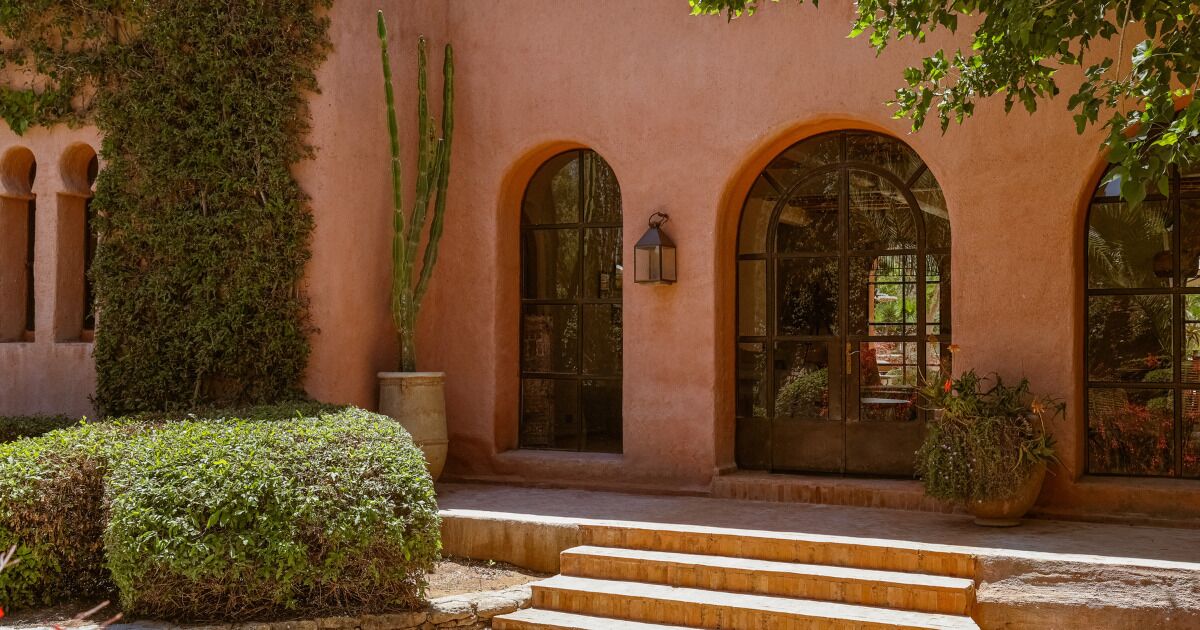 Un edificio con ventanas de arco, una escalera que conduce a la entrada y una planta de cactus.