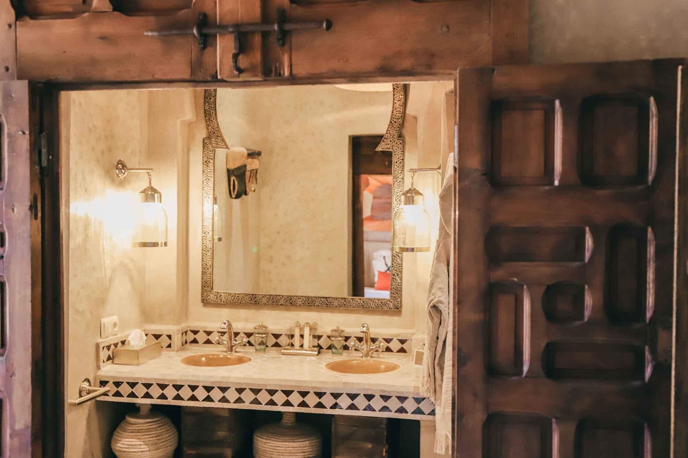 Un baño con un espejo grande, dos lavamanos y un borde de azulejos estampado.