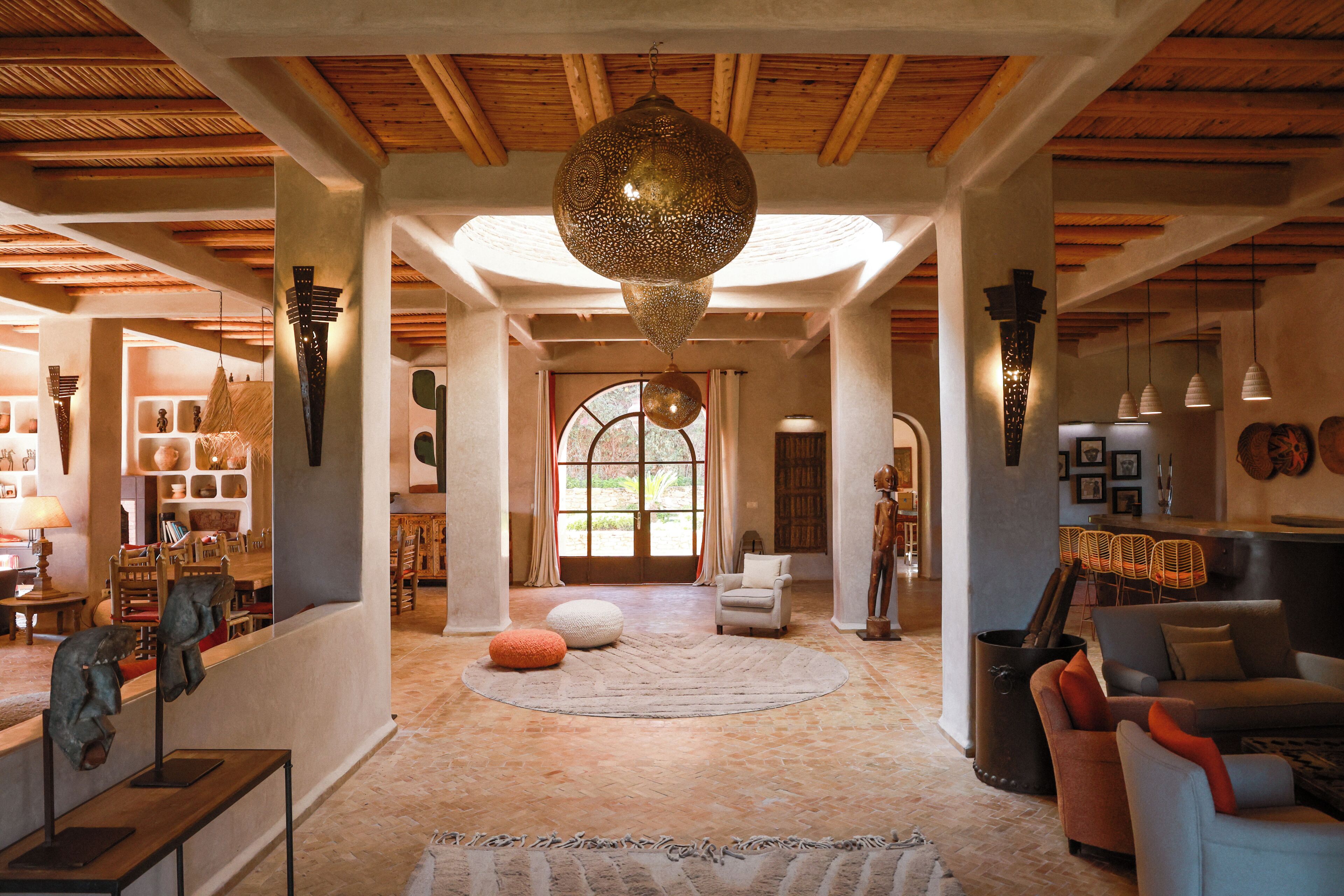 A spacious interior with a high ceiling, a large decorative hanging light, and a view through a glass door to an outdoor area.