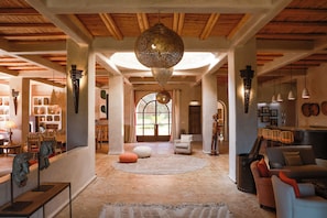 A spacious interior with a high ceiling, a large decorative hanging light, and a view through a glass door to an outdoor area.