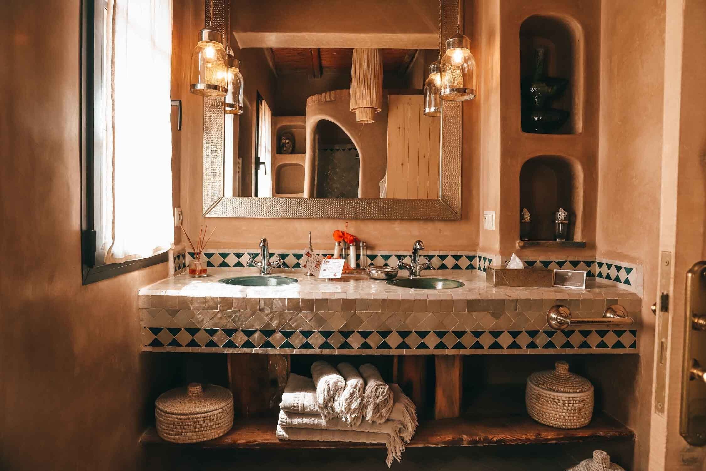 Un baño con un espejo grande, dos lavamanos y un perchero para toallas.
