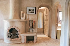 A stone fireplace with a bench, a framed picture on the wall, and an arched doorway leading to another room.