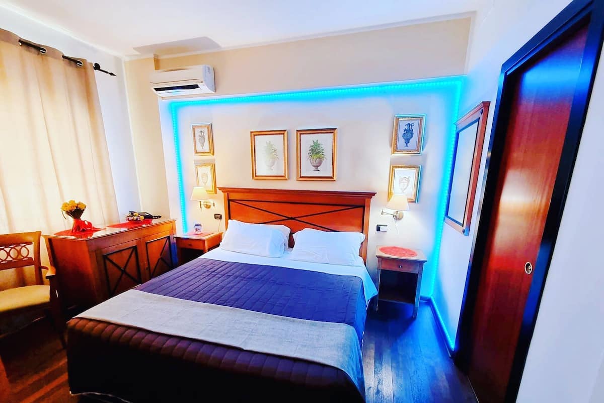 A hotel room with a large bed, bedside tables, a desk, and a chair.