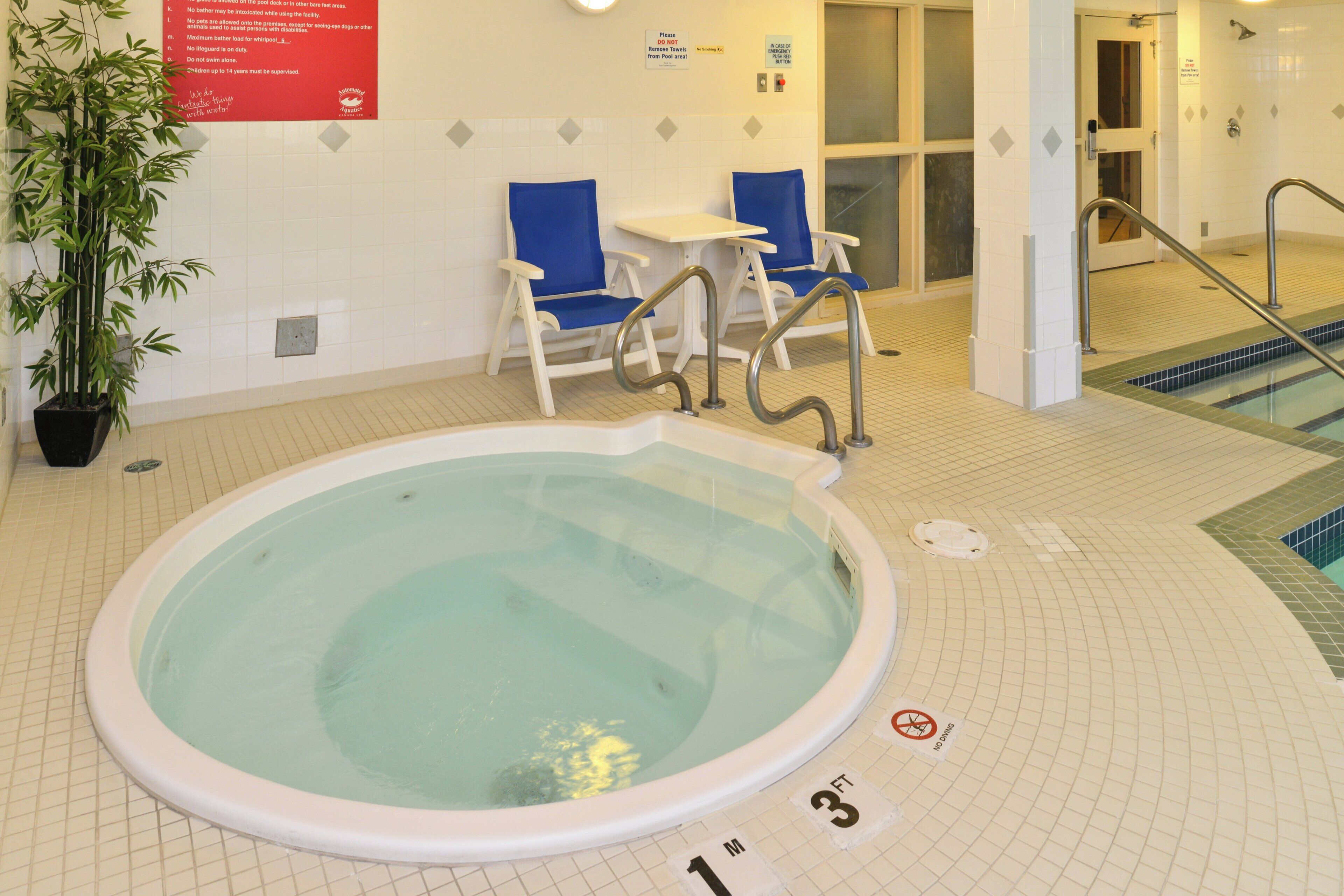 An indoor swimming pool with a lifeguard chair, a blue chair, and a sign indicating a depth of 3 feet.