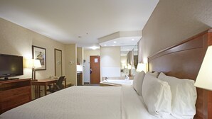 A hotel room with a large bed, a desk with a chair, a television, and a bathroom with a mirror. - Holiday Inn Express Hotel & Suites Edmonton North by IHG (Edmonton)