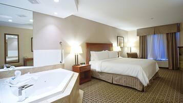 A hotel room with a large bed, a separate bathroom with a bathtub, and a small seating area.