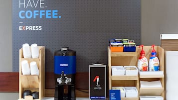 A coffee station with a coffee maker, cups, and coffee products.
