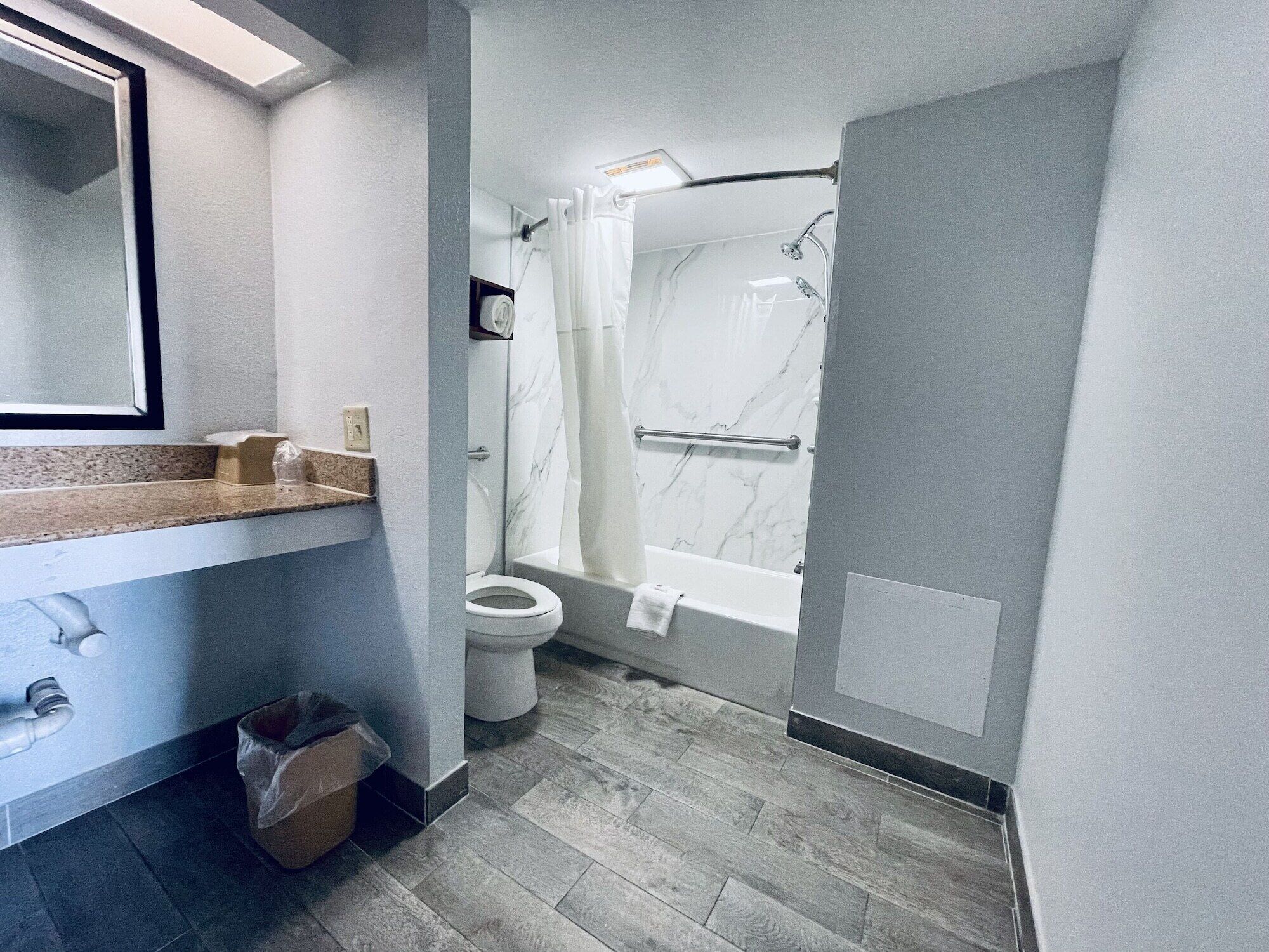 A modern bathroom with a marble shower, a toilet, and a sink with a towel rack.