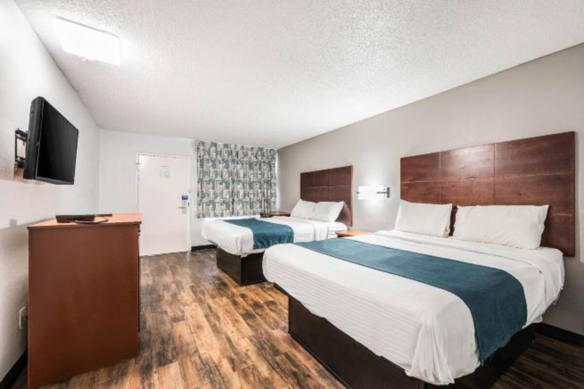 Une chambre d’hôtel avec deux lits, un bureau et une télévision.