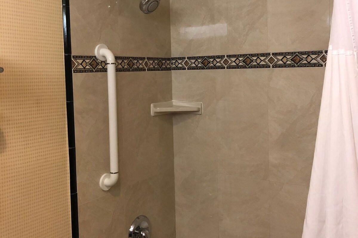 A bathroom with a shower, grab bar, and a bathtub.