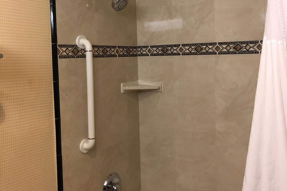 A bathroom with a shower, grab bar, and a bathtub.