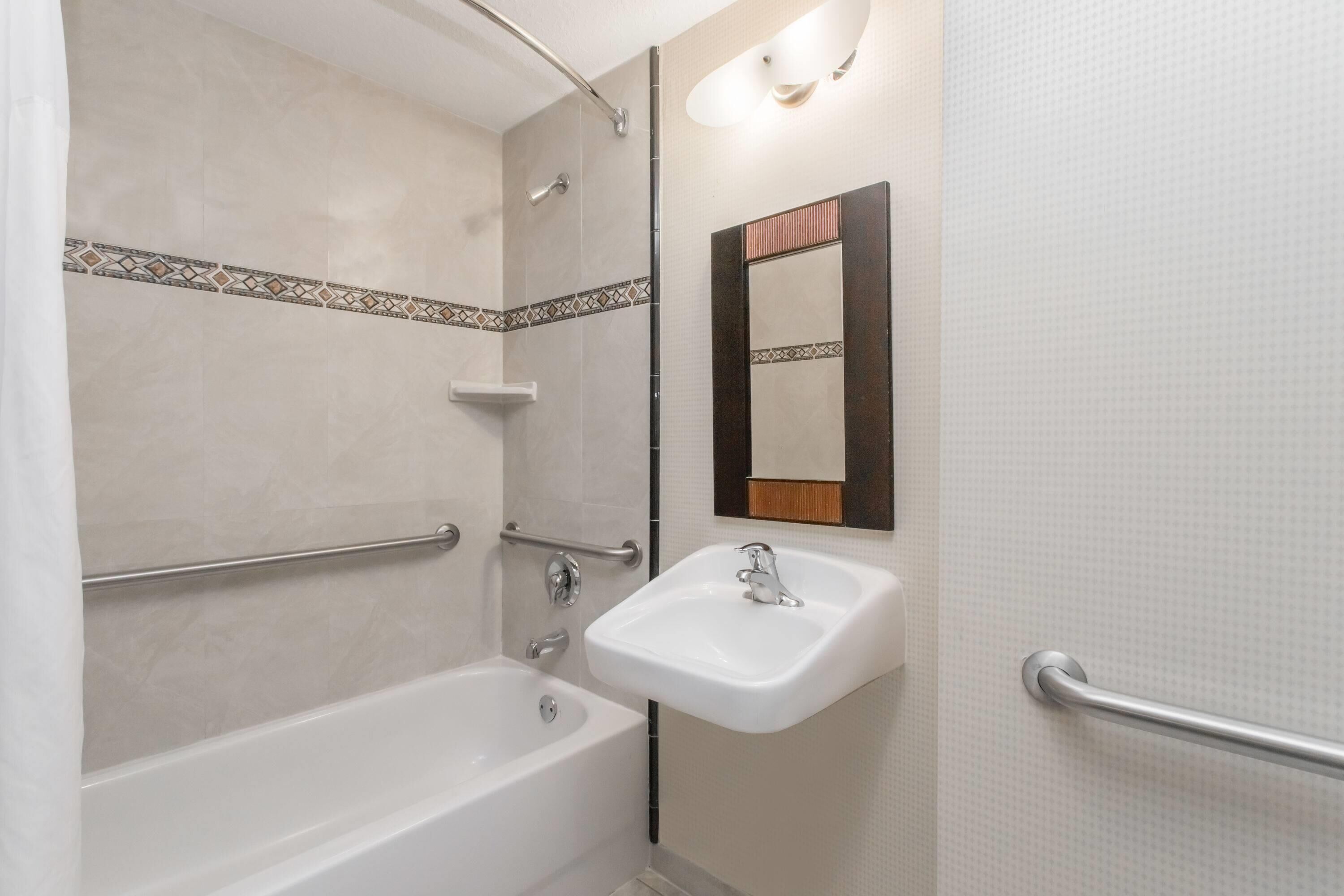 A bathroom with a bathtub, a sink, a mirror, and a shower.