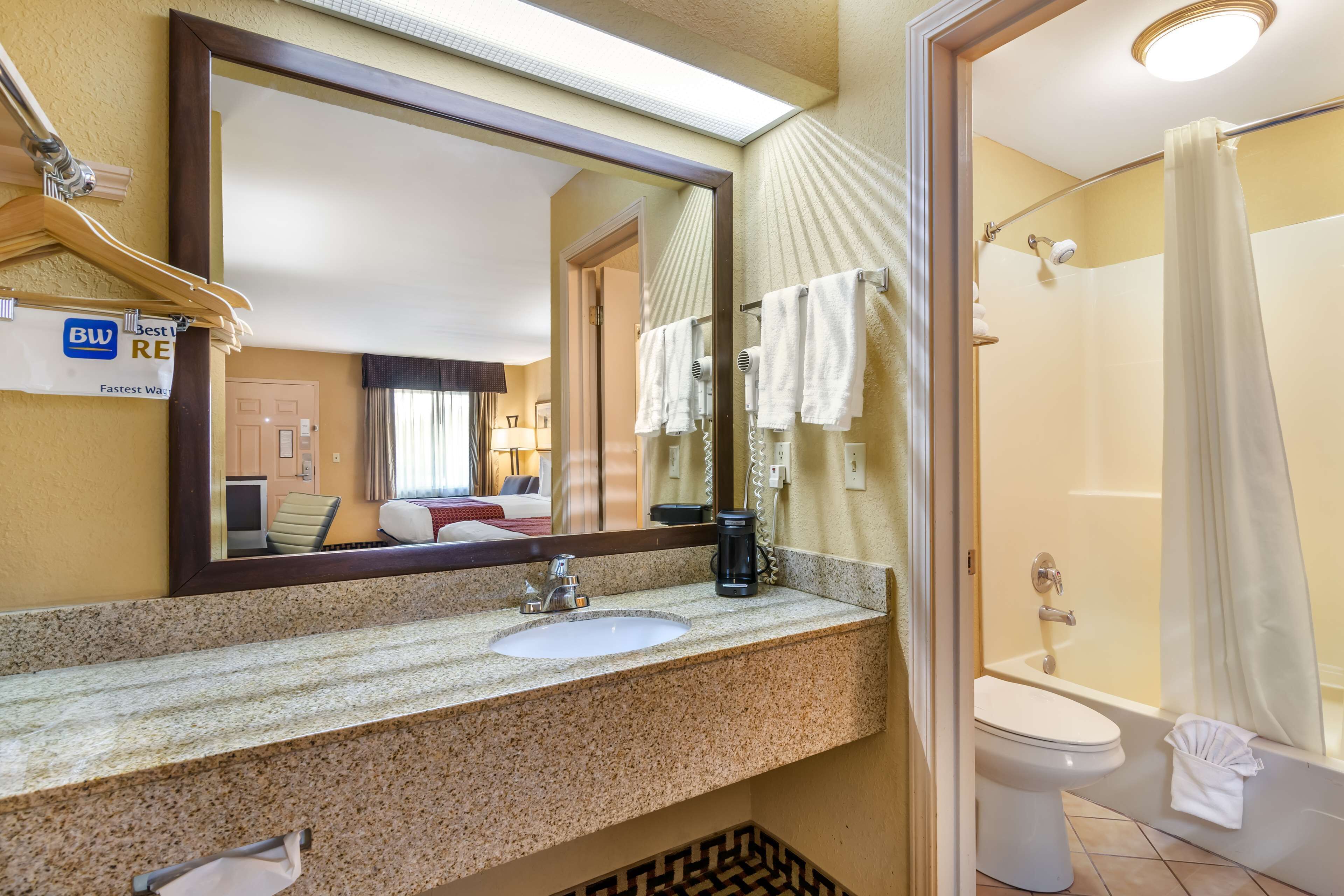 A hotel bathroom with a sink, mirror, and shower.