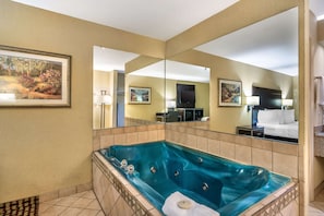 A hotel bathroom with a large bathtub, a mirror, and a painting on the wall. - Best Western Bradford Inn (Swainsboro)