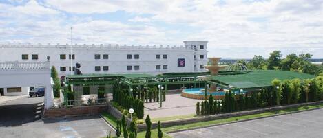 Un hotel grande con un patio central, una piscina y un edificio con techo verde.