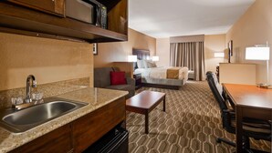 Una habitación de hotel con kitchenette, cama, escritorio y zona de estar.