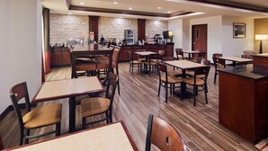 Un restaurante con varias mesas y cabinas, una zona de bar y un fondo de pared de piedra.