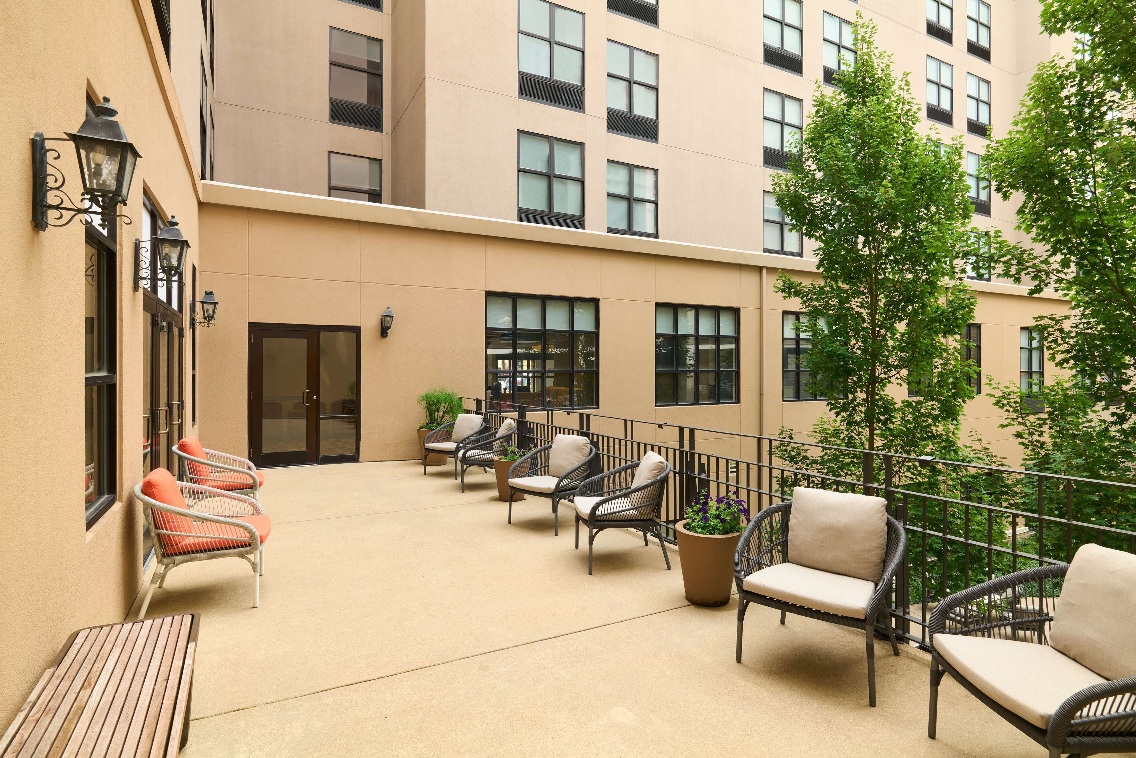 A courtyard with outdoor seating, a wooden bench, and potted plants.