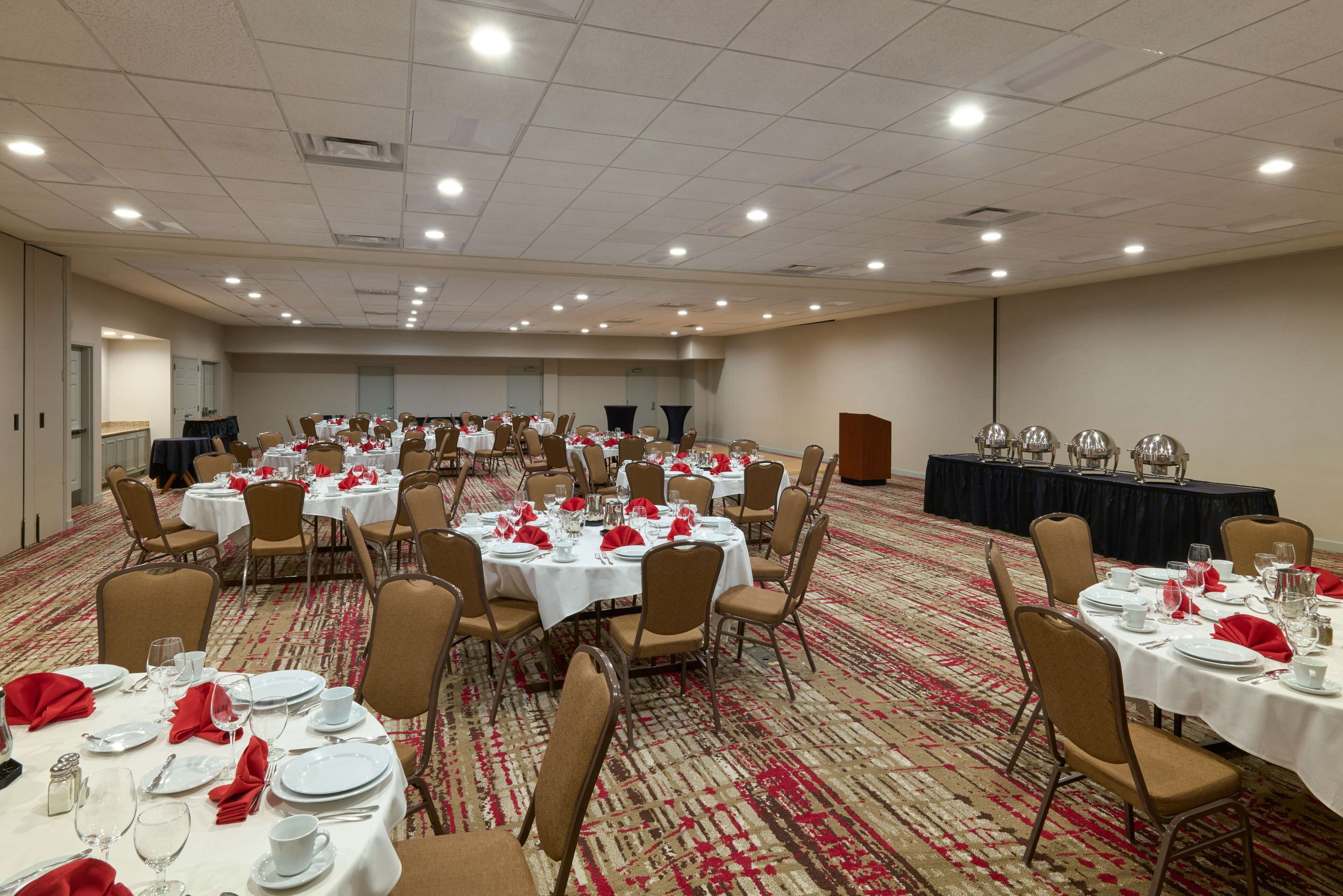 A conference room with multiple tables set for a formal event, equipped with chairs, tables, and a podium.