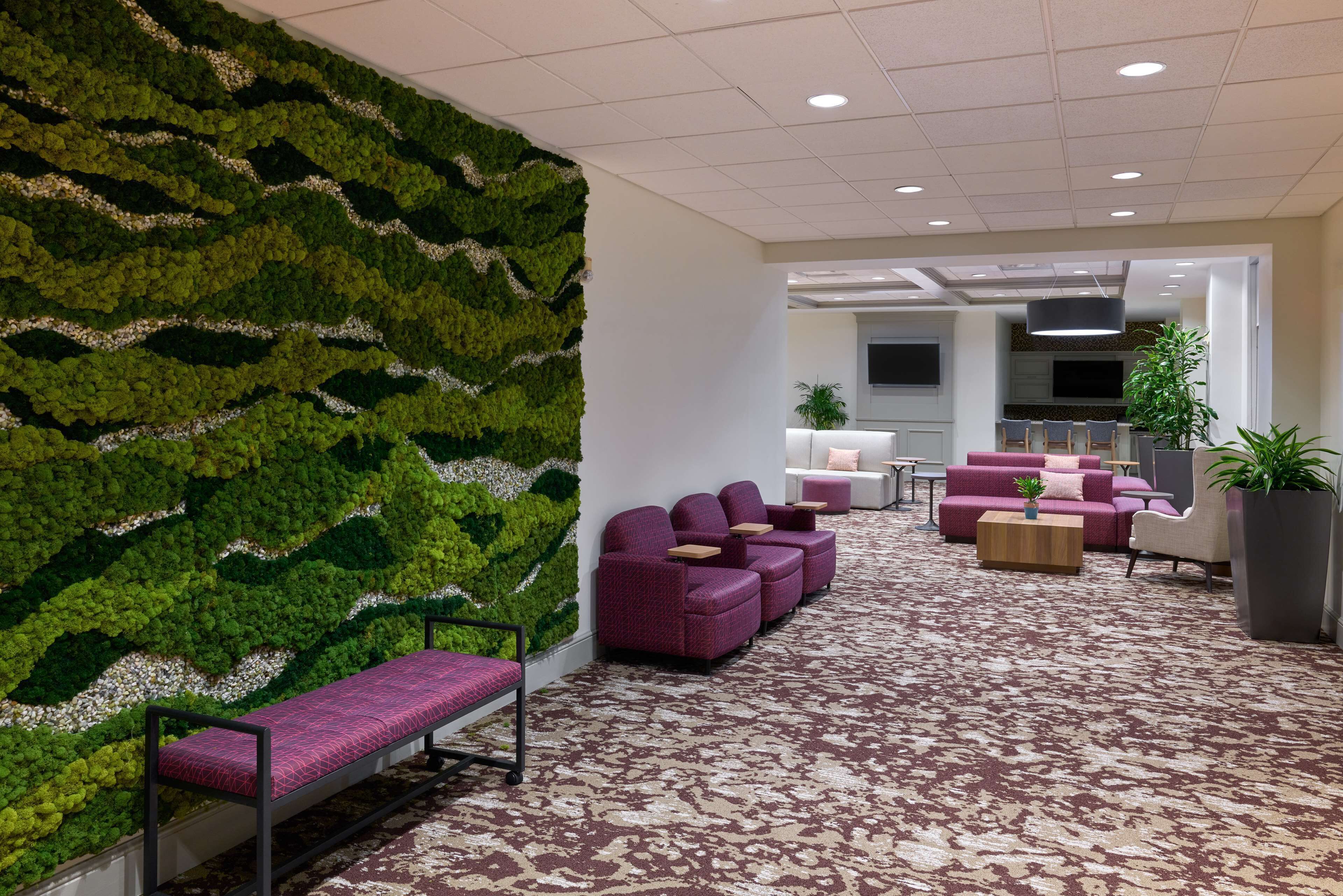 A lobby with a green wall, seating area, and a kitchen in the background.