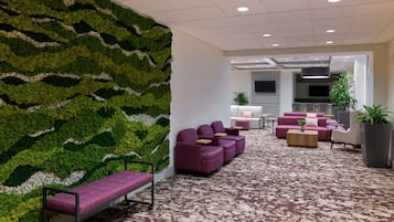 A lobby with a green wall, seating area, and a kitchen in the background.