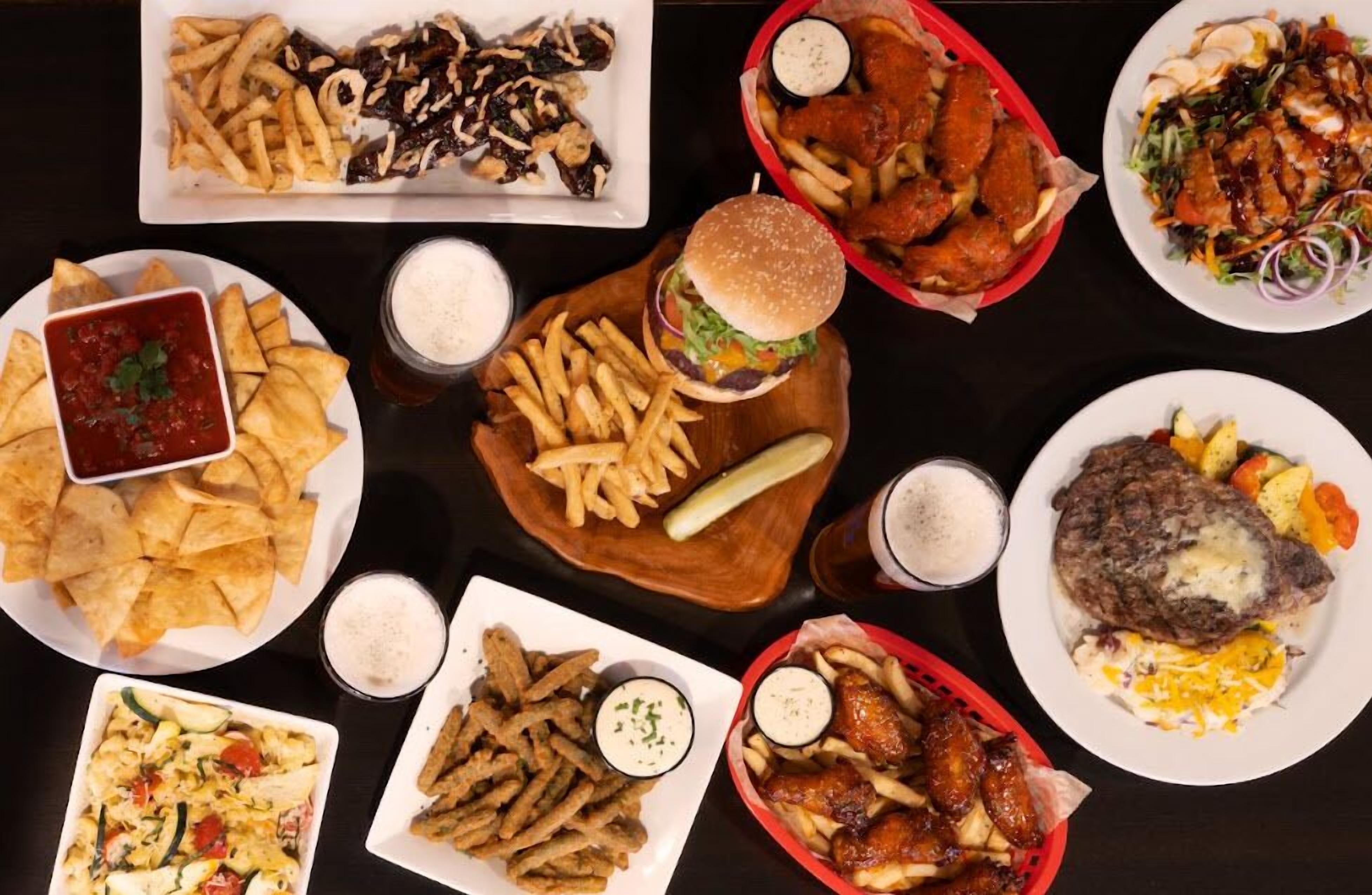 A variety of dishes including fries, burgers, and salads on a table.