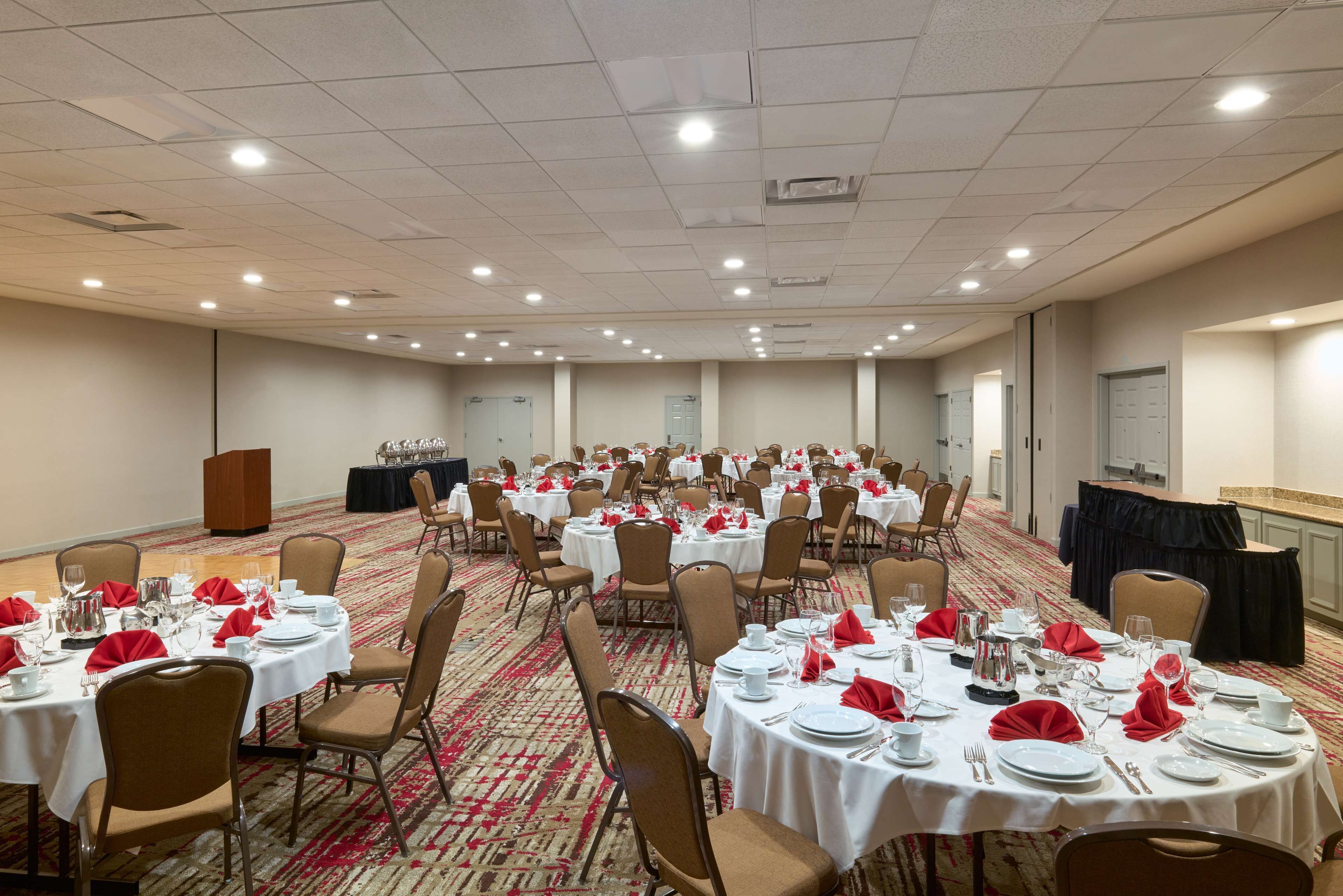 A conference room with multiple round tables, chairs, and a podium.