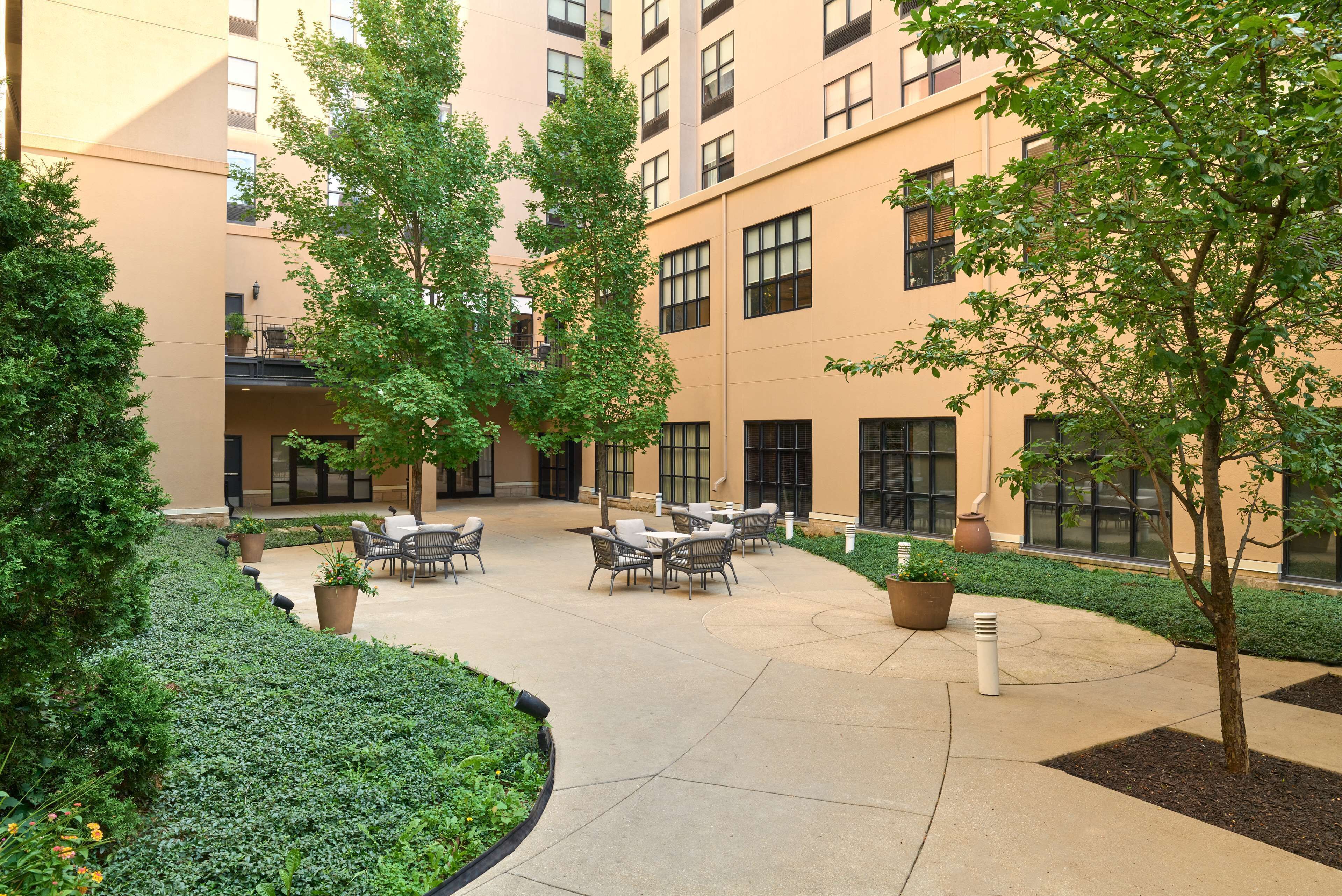 A courtyard with outdoor seating, potted plants, and a building with multiple windows and balconies.