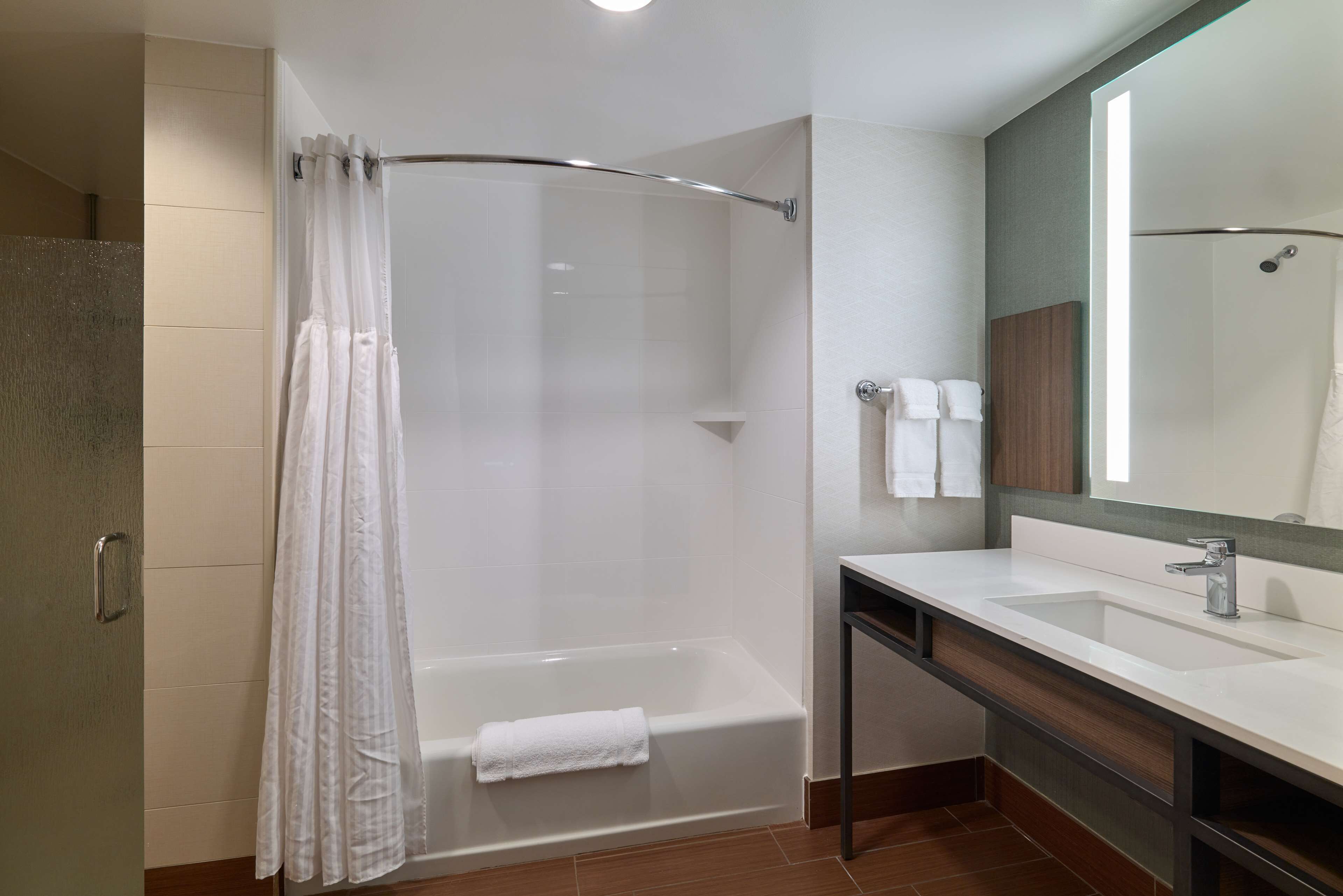 Un baño moderno con ducha, lavamanos y espejo.
