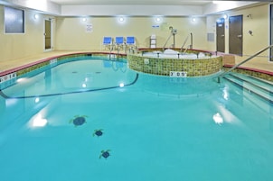 Piscina interna com borda revestida, banheira de hidromassagem e cadeira do salva-vidas.