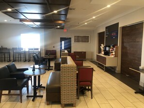 A modern cafe with seating arrangements, a coffee station, and a patterned wall. - Holiday Inn Express & Suites Woodward by IHG (Woodward)
