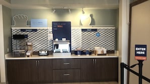 A bakery counter with a sign reading "FEELIN' FRESH THIS MORNING?" and a sign above it stating "THIS IS HOW WE ROLL E-PRESS." - Holiday Inn Express & Suites Woodward by IHG (Woodward)