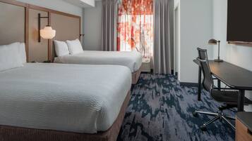 A hotel room with two beds, a desk, a chair, and a large window with curtains.