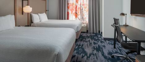 A hotel room with two beds, a desk, a chair, and a large window with curtains.