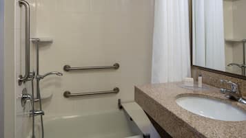 Bagno con vasca, lavabo e specchio. Sono presenti maniglie di sostegno per la sicurezza.