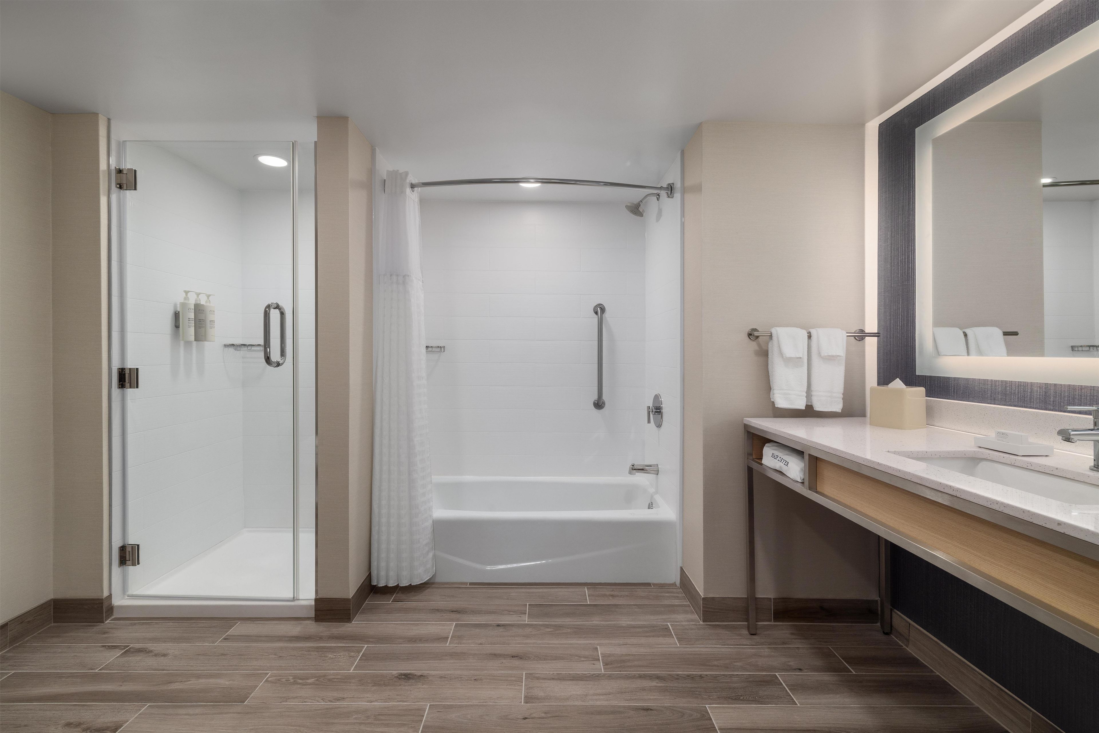 Une salle de bain moderne avec une douche à parois de verre, une baignoire et un meuble-lavabo avec un miroir.