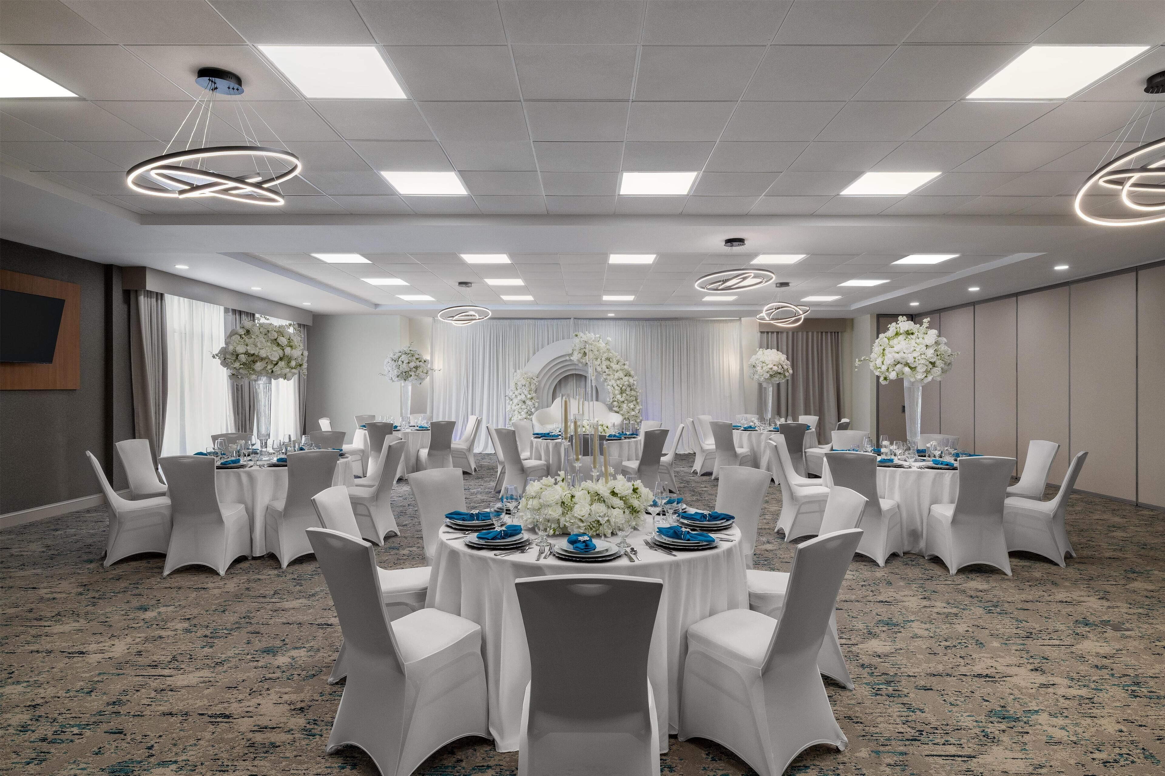 A conference room with round tables, white chairs, and floral centerpieces.