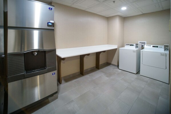 Una cocina con electrodomésticos de acero inoxidable, una encimera blanca y piso de baldosas.