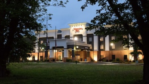 Un hôtel Hampton Inn au design moderne, avec une entrée imposante et une façade bien éclairée.