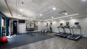 Une salle de sport équipée de tapis de course, de ballons d’exercice et d’appareils de musculation.