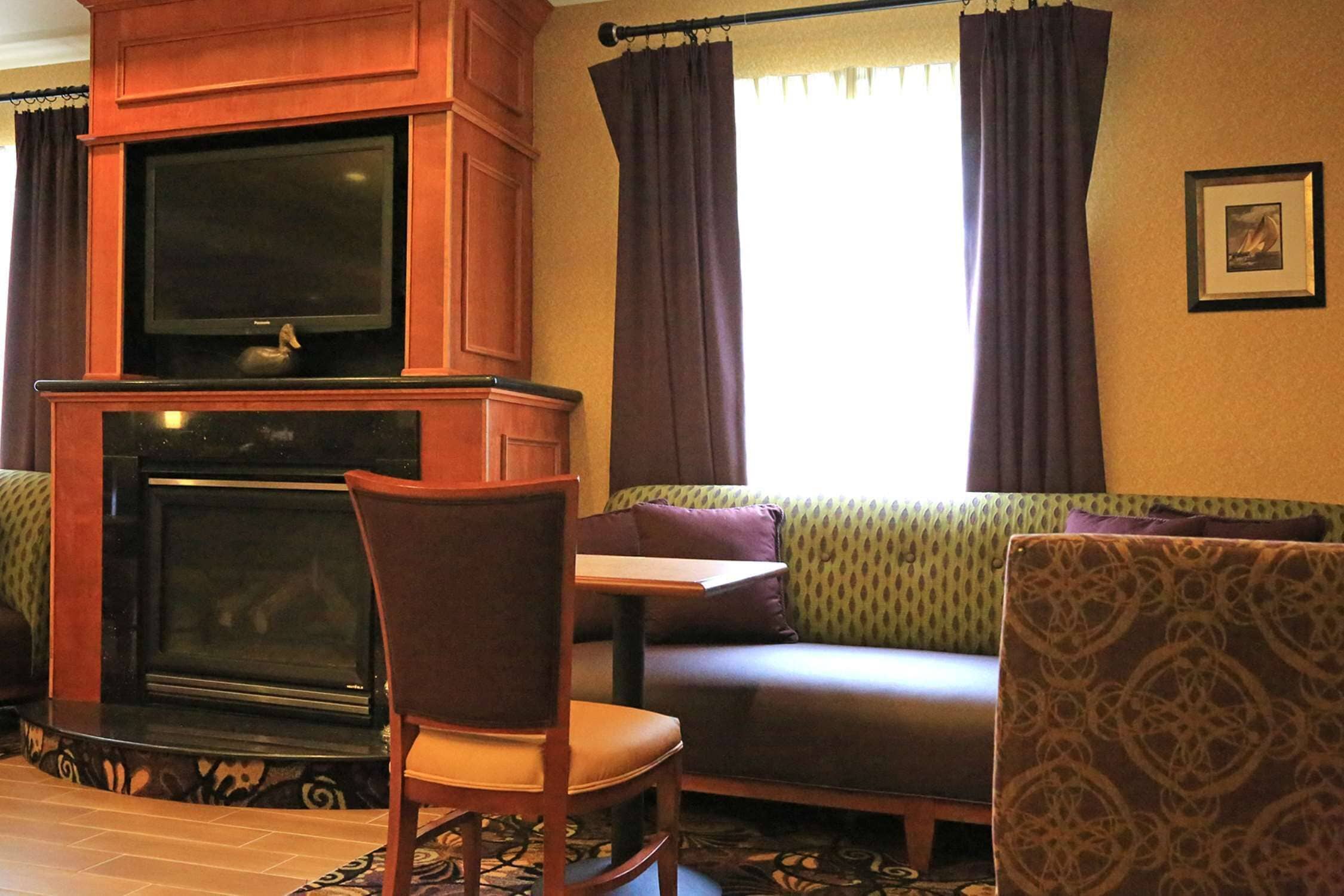 A living room with a fireplace, a television, a sofa, and a chair.