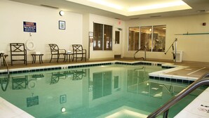 A swimming pool with a tiled edge, a lifeguard chair, and a sign on the wall.