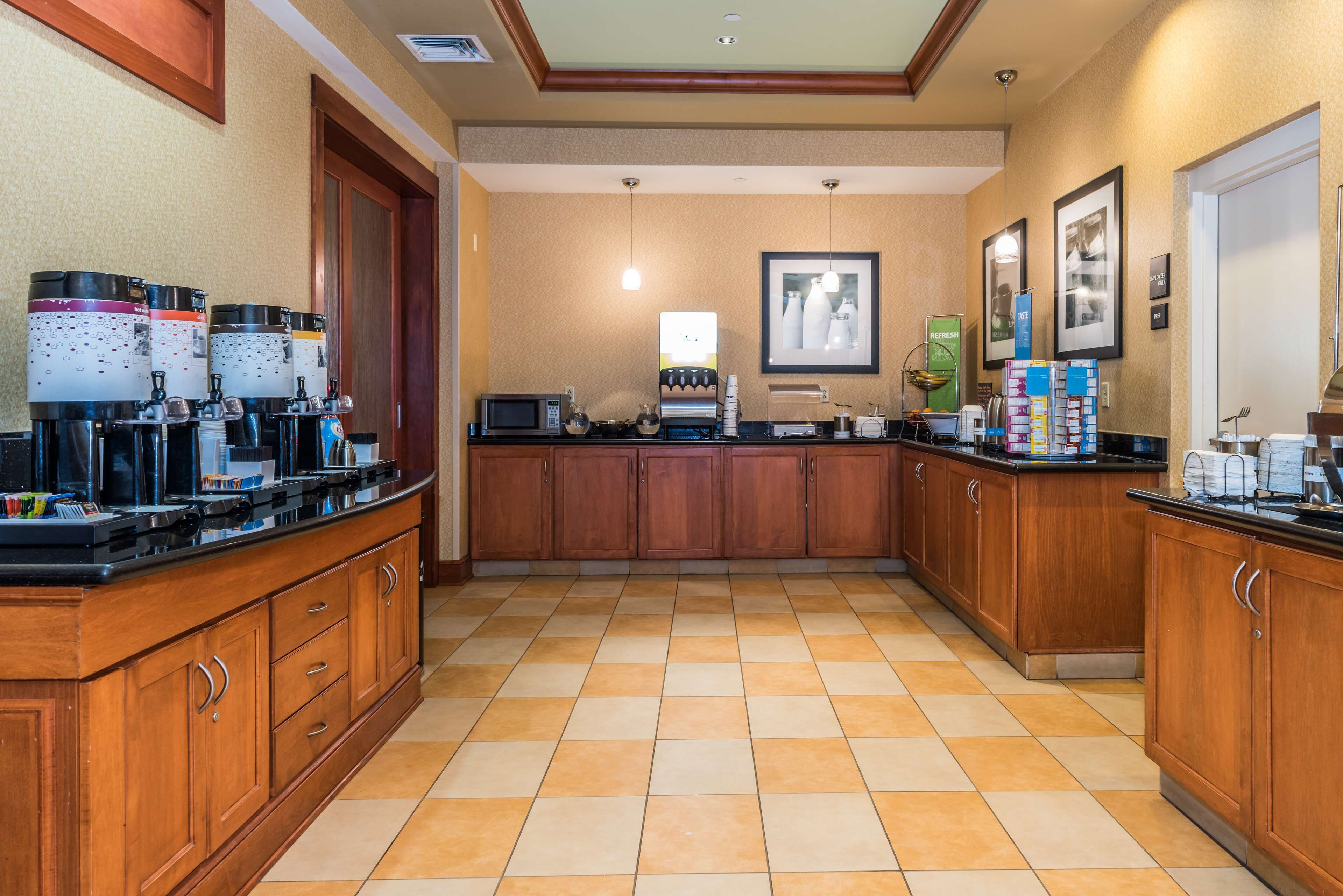 A kitchen with wooden cabinets, a tiled floor, and various appliances.