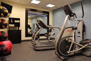 A gym with elliptical machines, a treadmill, and exercise balls.
