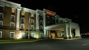 A Hampton Inn hotel with a brick facade, a large entrance, and a flagpole.