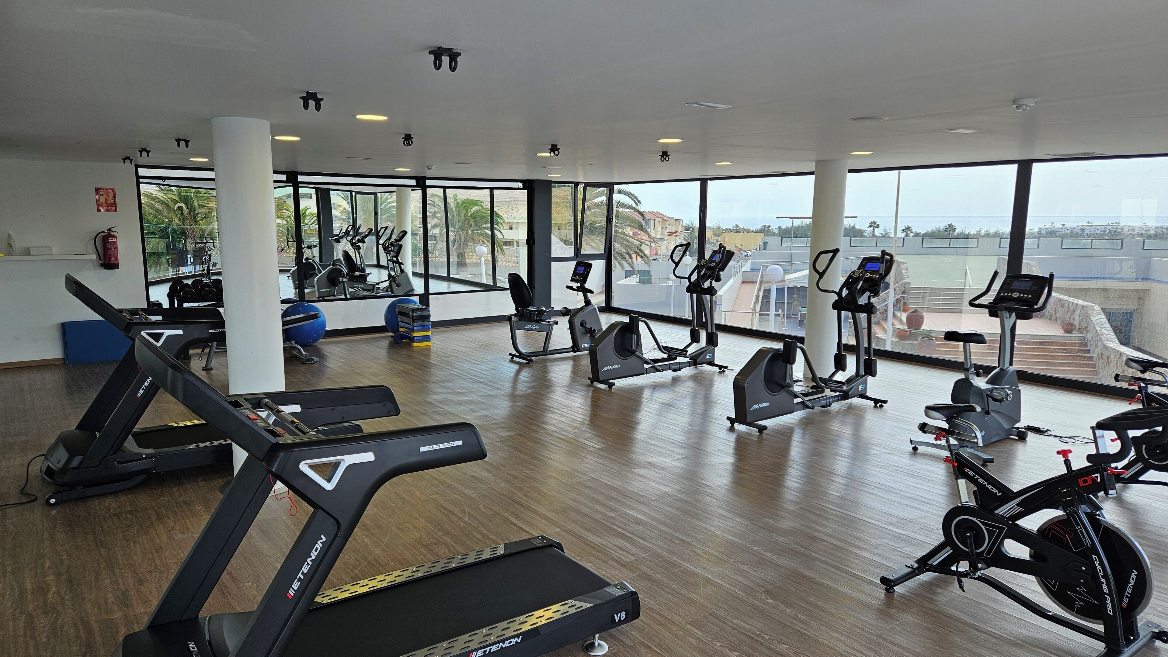 Un gimnasio con cintas de correr, bicicletas estáticas y pelotas de ejercicio.