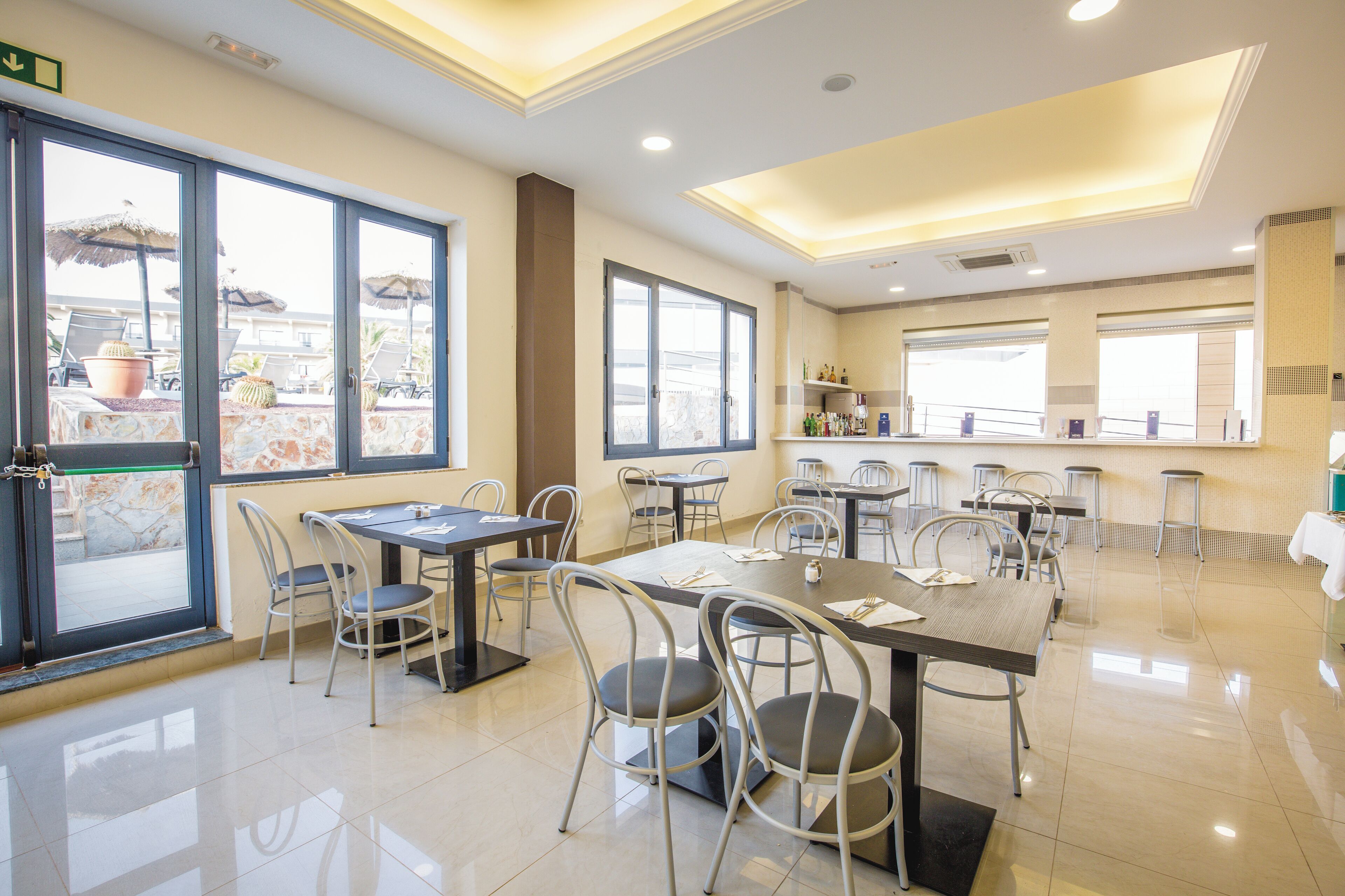 A spacious dining area with multiple tables and chairs, large windows with a view, and a clean, modern interior design.